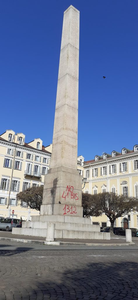 The Siccardi Obelisk in Piazza Savoia, Turin, on the morning of March 5, 2023, after the anarchists' protest on March 4, 2023, with red spraypaint on the base of the obelisk which says "No 41-bis" and "1312," references to the "hard time" penal code and a numerical code for ACAB, or All Cops are Bastards, with a black paintball mark to the left of the red spraypaint.