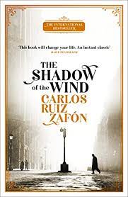 Off the shelf, Book cover for The Shadow of the Wind by Carlos Ruiz Zafón showing an old black and white photograph of a Barcelona city street with a man in a dark overcoat walking towards a street lamp on a misty morning or late afternoon. 