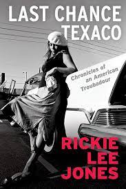 Book cover of Rickie Lee Jones autobiography, Last Chance Texaco, showing black and white photo of the artist leaning against a classic car, wearing her signature beret, a dark sleeveless top and a skirt, holding a bottle of liquor in a paper bag, barefoot, with her name in all capital letters in a red font